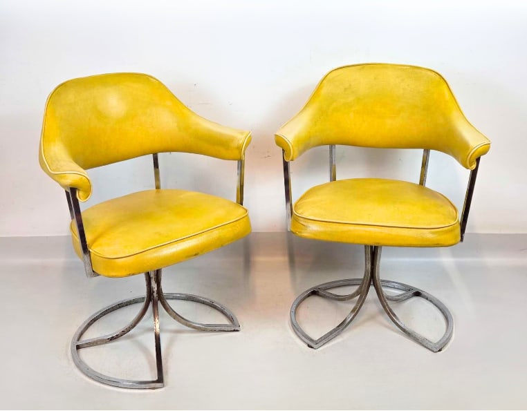 VINTAGE MID CENTURY CHROME AND YELLOW VINYL SWIVEL ARMCHAIRS: *Pair of retro swivel armchairs upholstered in vibrant yellow faux leather on sculptural ribbon style chrome bases. Approximate Dimensions: 31"h x 24"w x 20"d Artist or Maker: Unknown