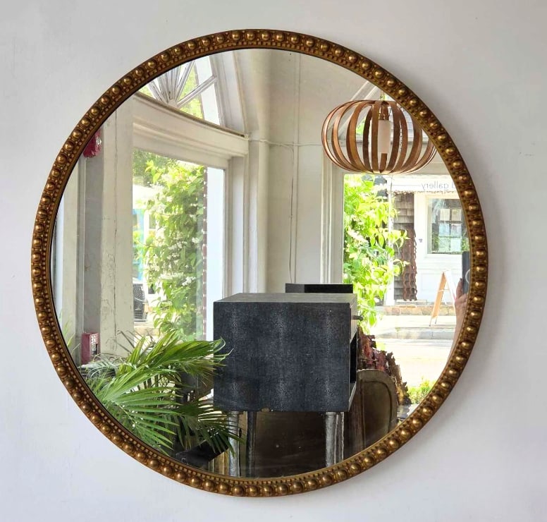 VINTAGE REGENCY STYLE CIRCULAR GILTWOOD WALL MIRROR: Round hanging plate glass mirror bordered by a molded wooden frame with stylized bead detailing and an antiqued gold finish. Approximate Dimensions: 30"dia Artist or Maker: Unknown Provenance: A N