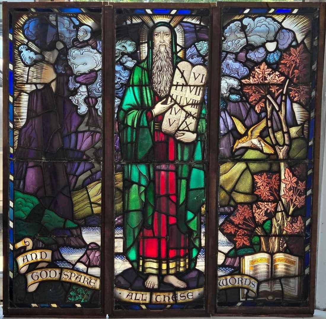 ANTIQUE GOTHIC REVIVAL LEADED STAINED GLASS THREE-PANEL TRIPTYCH CHURCH WINDOW IRELAND: Three-panel antique ecclesiastical leaded stained glass altar church window triptych depicting Moses with the Ten Commandments tablets flanked by a mountainous landscape and an open Bible reading Mala