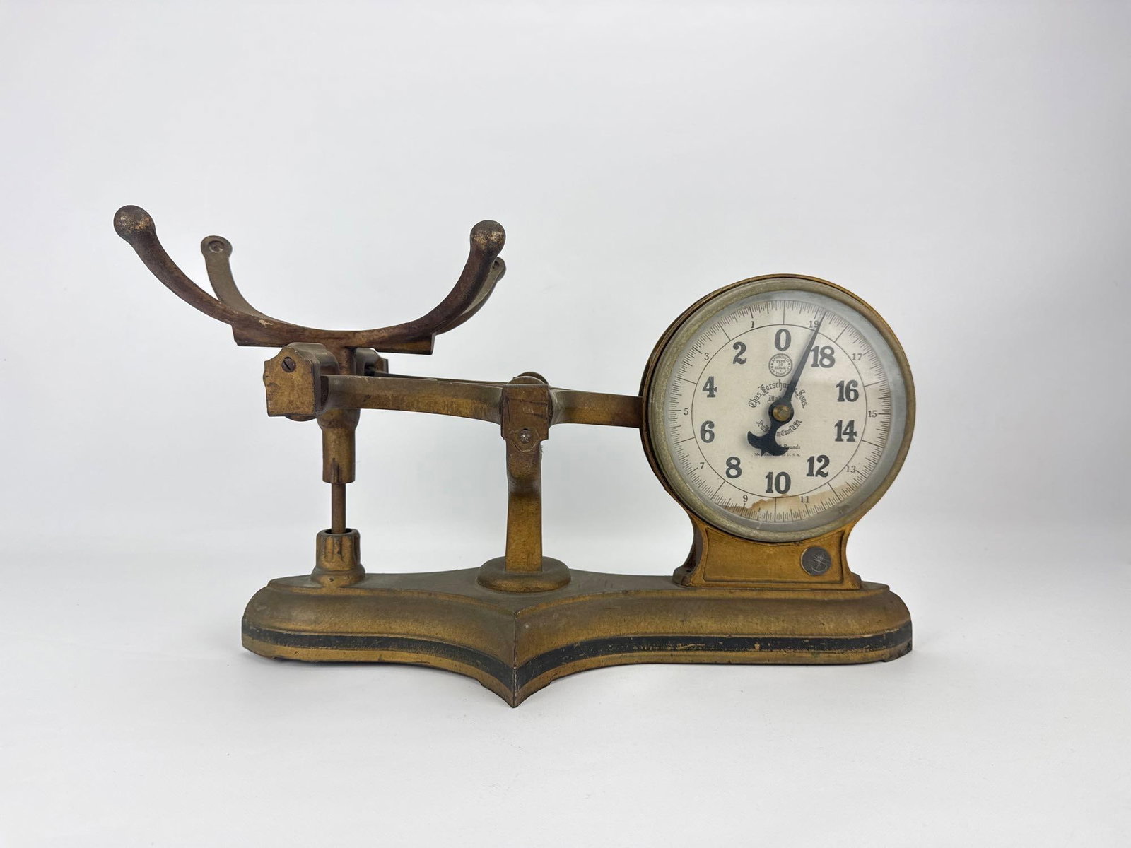 CHAS. FORSCHNER & SONS BRASS DOUBLE SIDED GLASS FACE STORE SCALE: Vintage brass countertop mercantile scale with a curved cradle arm, dual-sided round glass-covered dials, and weighted pointer needles Approximate Dimensions: 10.75” H X 19.75” W X 7.5&rdq
