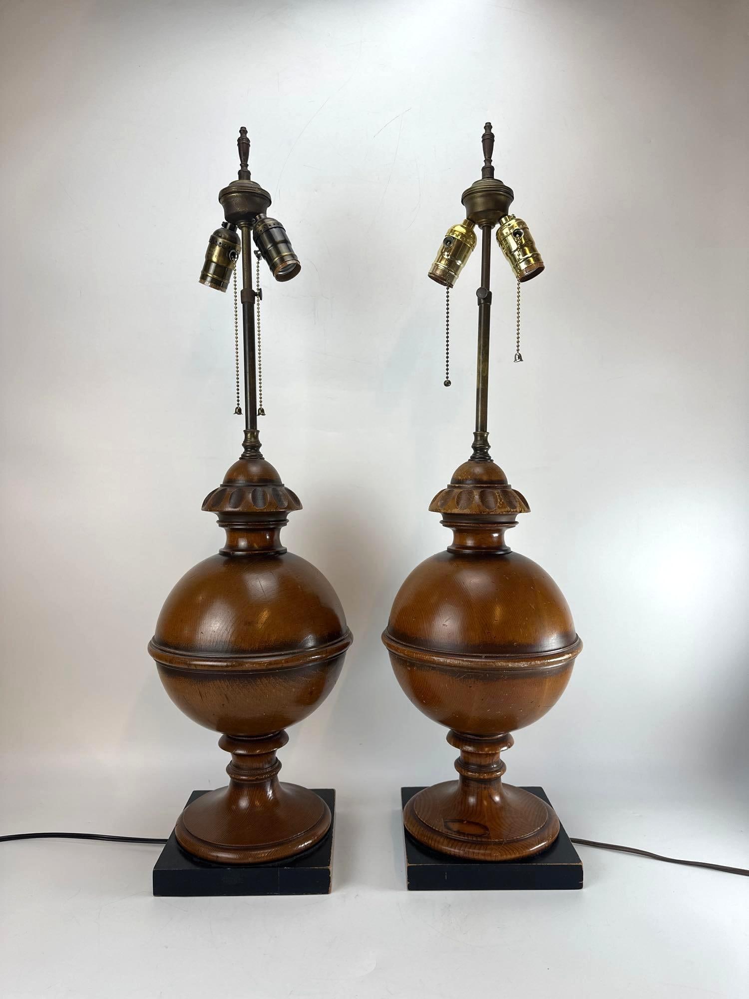 PAIR OF MID CENTURY FREDERICK COOPER STYLE TURNED WOOD TABLE LAMPS: A pair of vintage mid-century modern turned wood baluster-form table lamps resting on square ebonized wooden plinth bases with double-cluster pull chain sockets. Approximate Dimensions: 32” x 9&