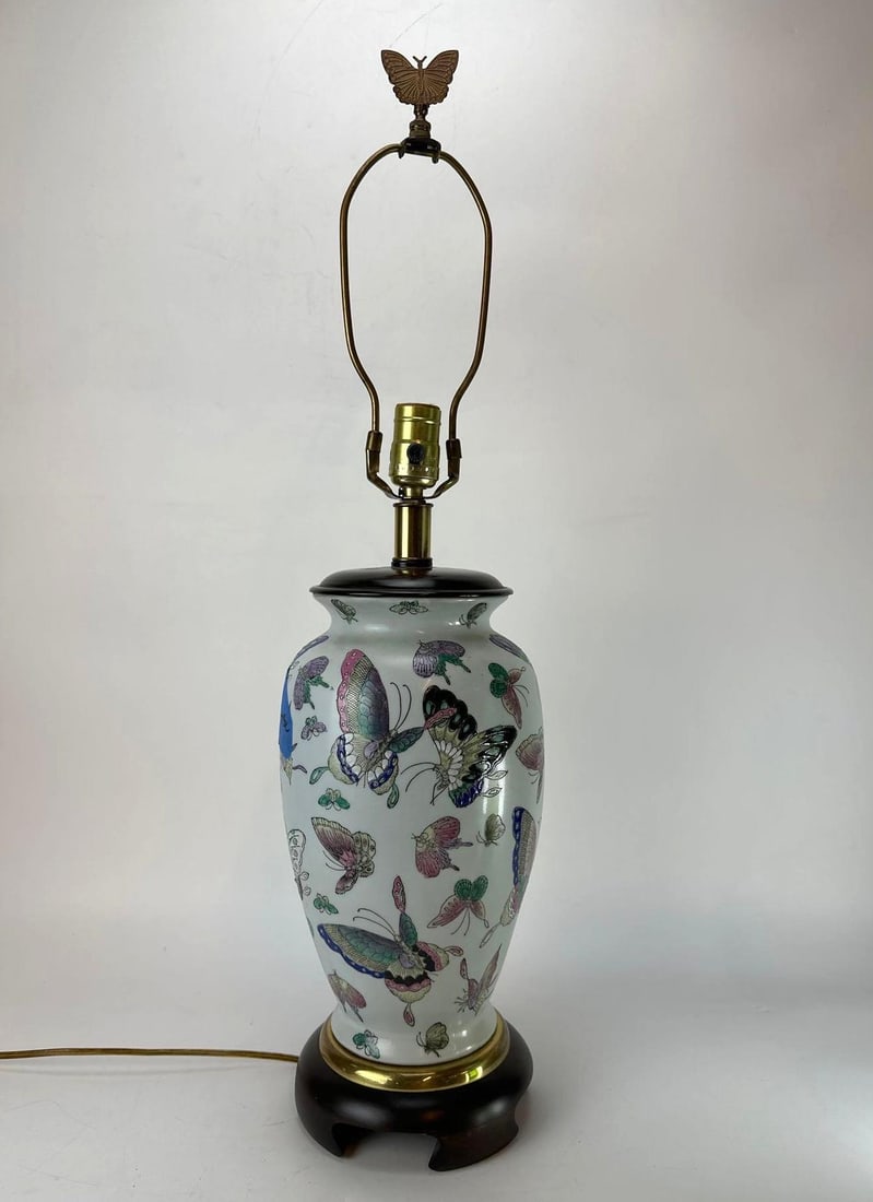 CHINESE FAMILLE ROSE PORCELAIN BUTTERFLY VASE LAMP: A vintage Chinese famille rose porcelain vase mounted as a table lamp on a wooden base decorated with hand painted butterflies in flight and topped with a brass butterfly finial. Approximate Dimension