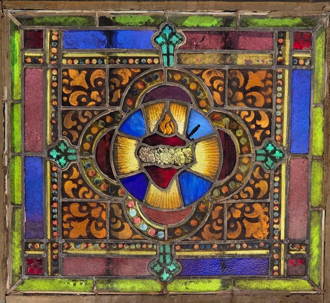 AMERICAN ANTIQUE LEADED STAINED GLASS CHURCH WINDOW WITH IMMACULATE HEART (1 of 4): A religious leaded stained glass architectural window panel depicting the Immaculate Heart of Mary pierced by a sword surrounded by roses and radiant rays, contained within its original wooden frame. 