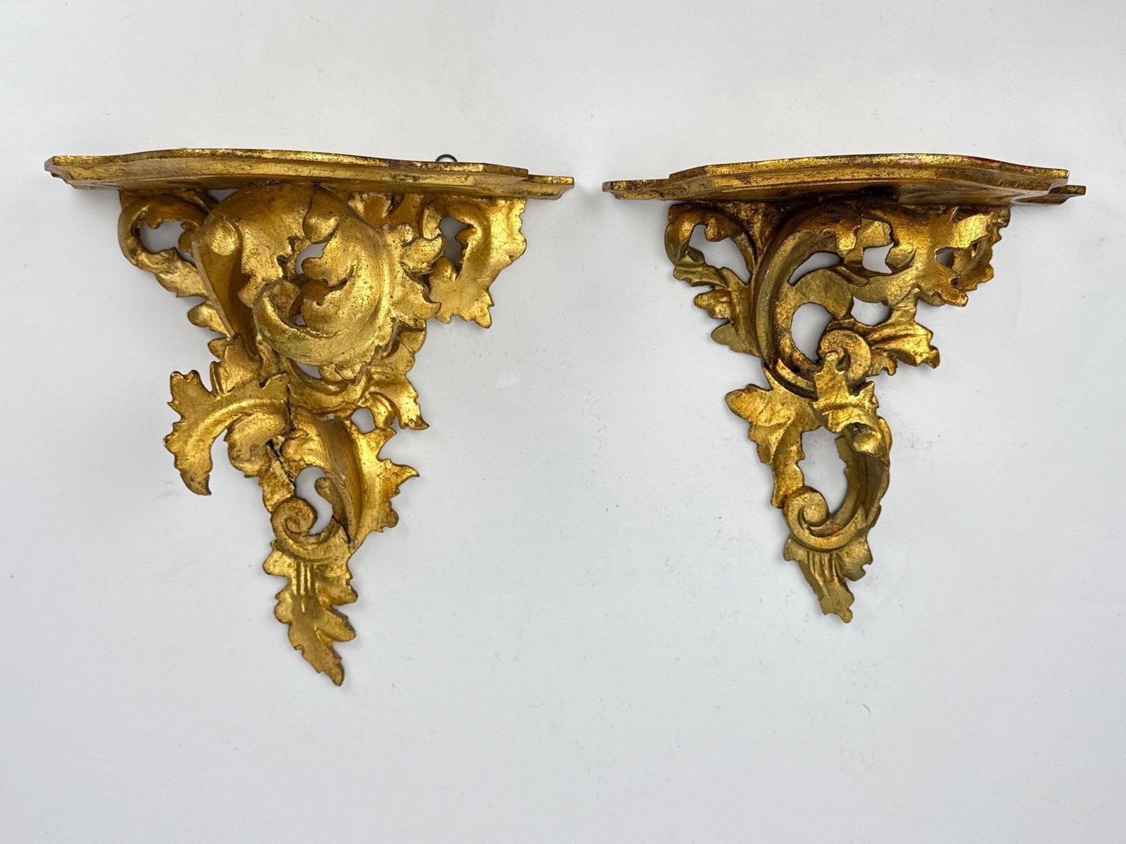 PAIR OF ITALIAN ROCOCO STYLE GILTWOOD WALL BRACKETS: Pair of hand-carved giltwood wall consoles with shaped shelves over pierced acanthus scroll and rocaille supports. Approximate Dimensions: Larger 11” H X 10.5” W X 5.75” D Artist or 