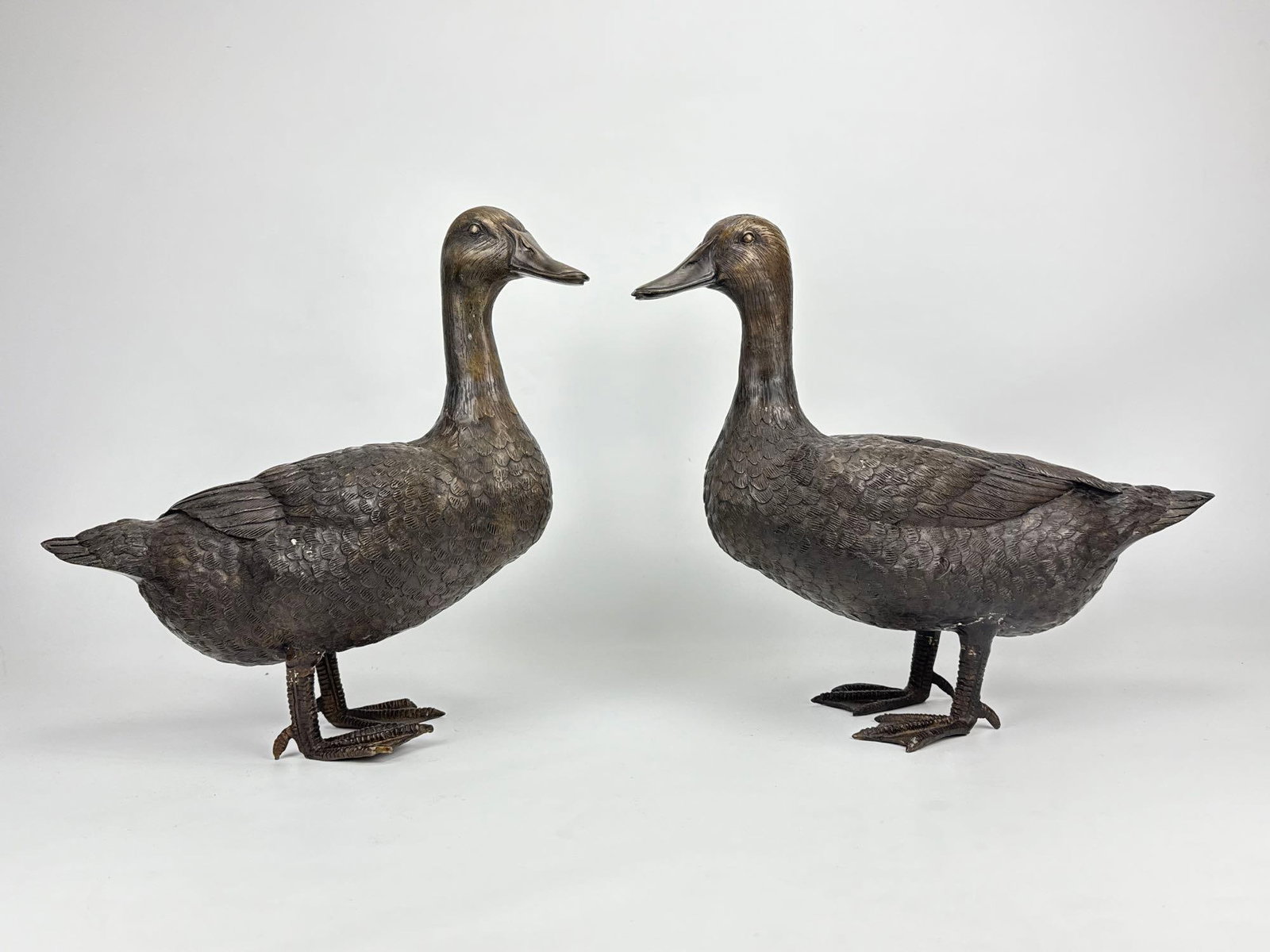 PAIR OF LIFE-SIZE CAST BRONZE DUCK GARDEN SCULPTURES: Pair of heavy cast bronze waterfowl statues of standing ducks with realistically detailed plumage and dark patination. Approximate Dimensions: Larger: 16.5” H X 17” W X 6.25” D Artis