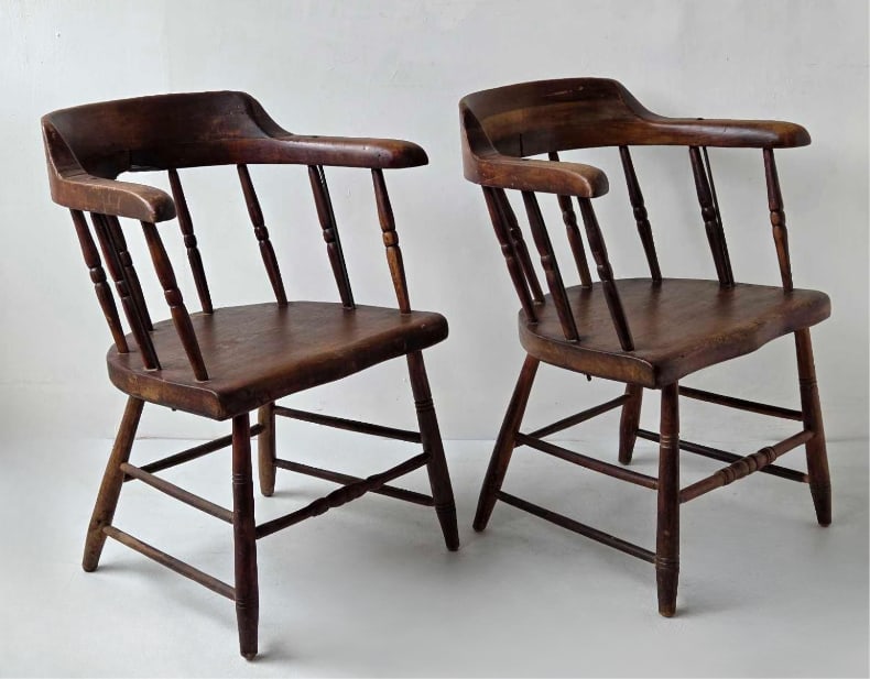 PAIR OF ANTIQUE ENGLISH SMOKER'S BOW / CAPTAIN'S ARMCHAIRS: Matching pair of 19th-century country style wooden armchairs, each featuring a low curved spindle backrest, broad contoured seat, and turned legs joined by a double H-stretcher. Approximate Dimensions