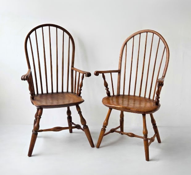TWO ANTIQUE AMERICAN COLONIAL REVIVAL WINDSOR HIGH BACK ARMCHAIRS: Pair of antique mixed-wood Windsor continuous-arm style high-back dining chairs, each featuring a classic multi-spindle backrest, molded plank seat, and splayed turned legs joined by an H-stretcher. A
