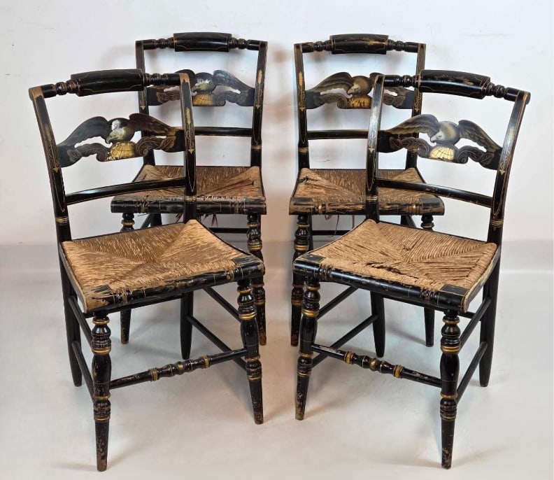 SET OF FOUR HITCHCOCK RUSH SEAT CHAIRS WITH EAGLE MOTIF: Four antique stenciled Hitchcock dining chairs with woven rush seats, gold-painted eagle splats, and turned legs, showing significant wear and paint loss to the finish and rush. As is condition. Appro