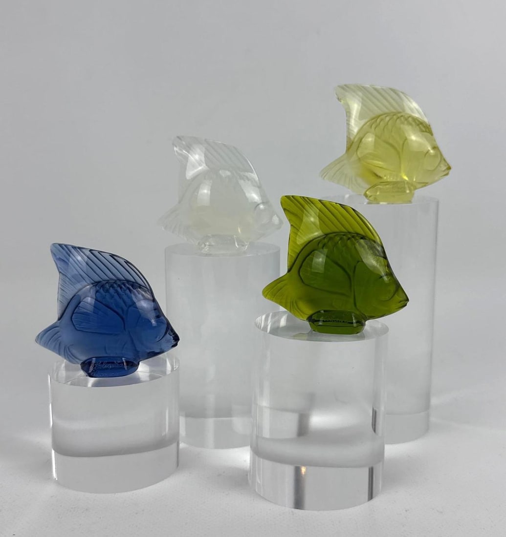 SET OF 4 LALIQUE FRANCE MOLDED ART GLASS FISH FIGURINES WITH BOX: Four frosted and clear crystal sculpture fish in blue, green, yellow, and clear colorways sitting atop graduated cylindrical acrylic presentation plinths Approximate Dimensions: 2” H X 2” 