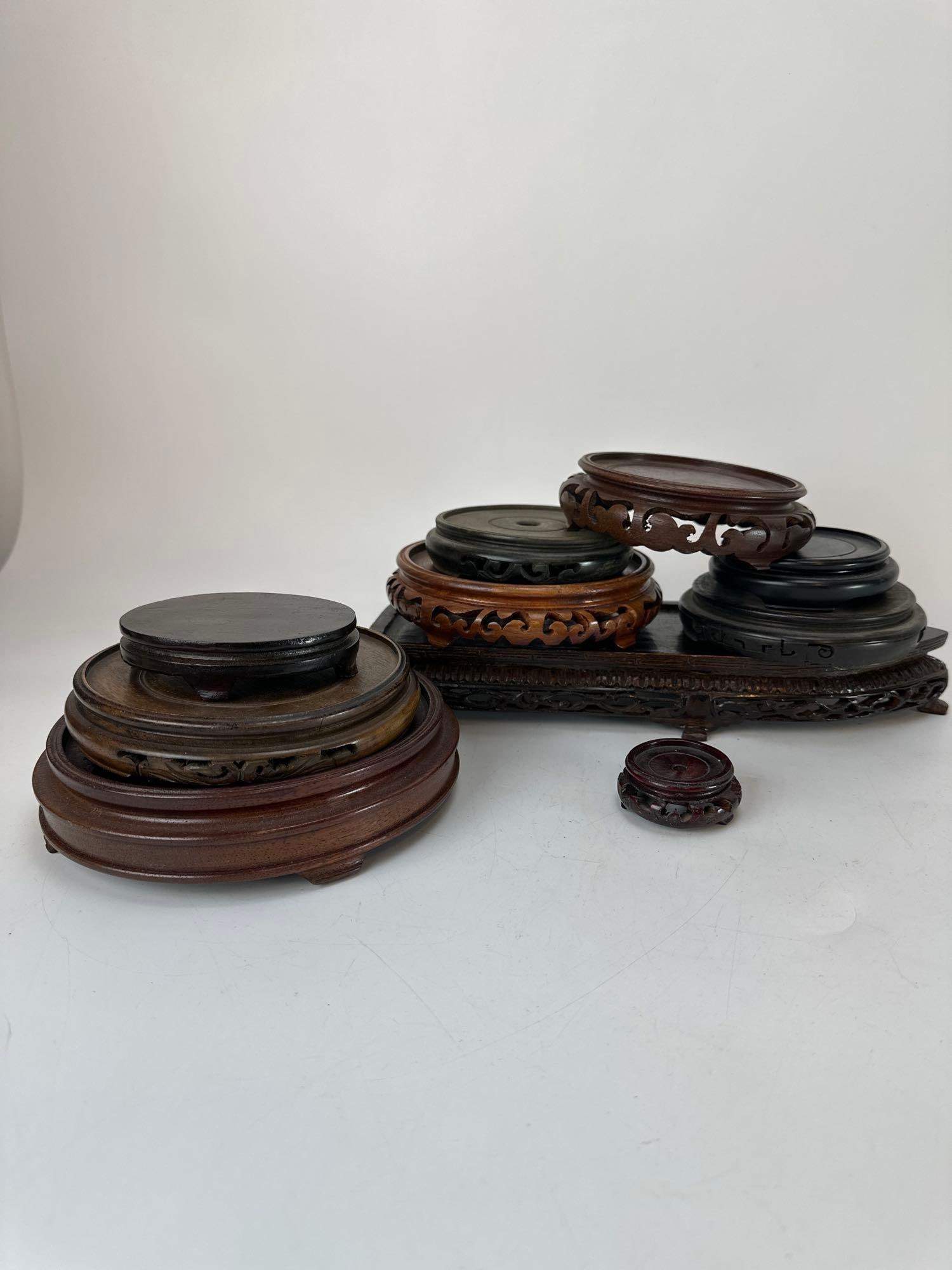 COLLECTION OF VINTAGE CHINESE CARVED HARDWOOD VASE AND BOWL STANDS - TEN PIECE SET: Ten-piece collection of vintage Chinese carved hardwood display stands in assorted shapes and sizes, including round, rectangular, and oval formats, featuring traditional pierced aprons, ruyi-form