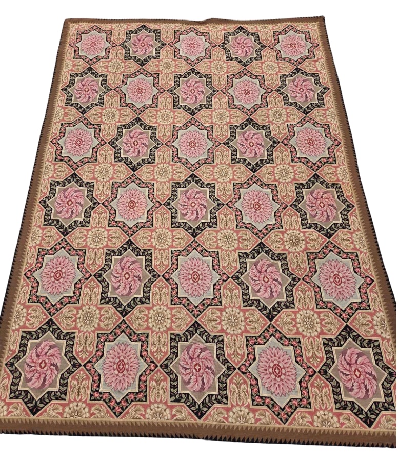 VINTAGE FLORAL MOTIF NEEDLEPOINT WOOL RUG: Mid-sized handmade wool needlepoint area rug configured with a geometric repeat lattice of eight-pointed stars framing pink floral rosettes against a beige and terracotta scrolled background, Approxim