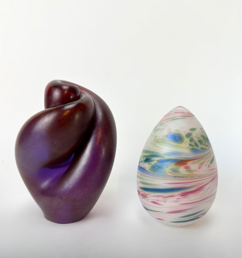 TWO-PIECE STUDIO ART GLASS PAPERWEIGHT AND SCULPTURE LOT: An iridescent purple abstract twisted glass form together with a multi-colored swirled egg-shaped paperweight collectible Approximate Dimensions: 5”x5”x7” Artist or Maker: Unknown</