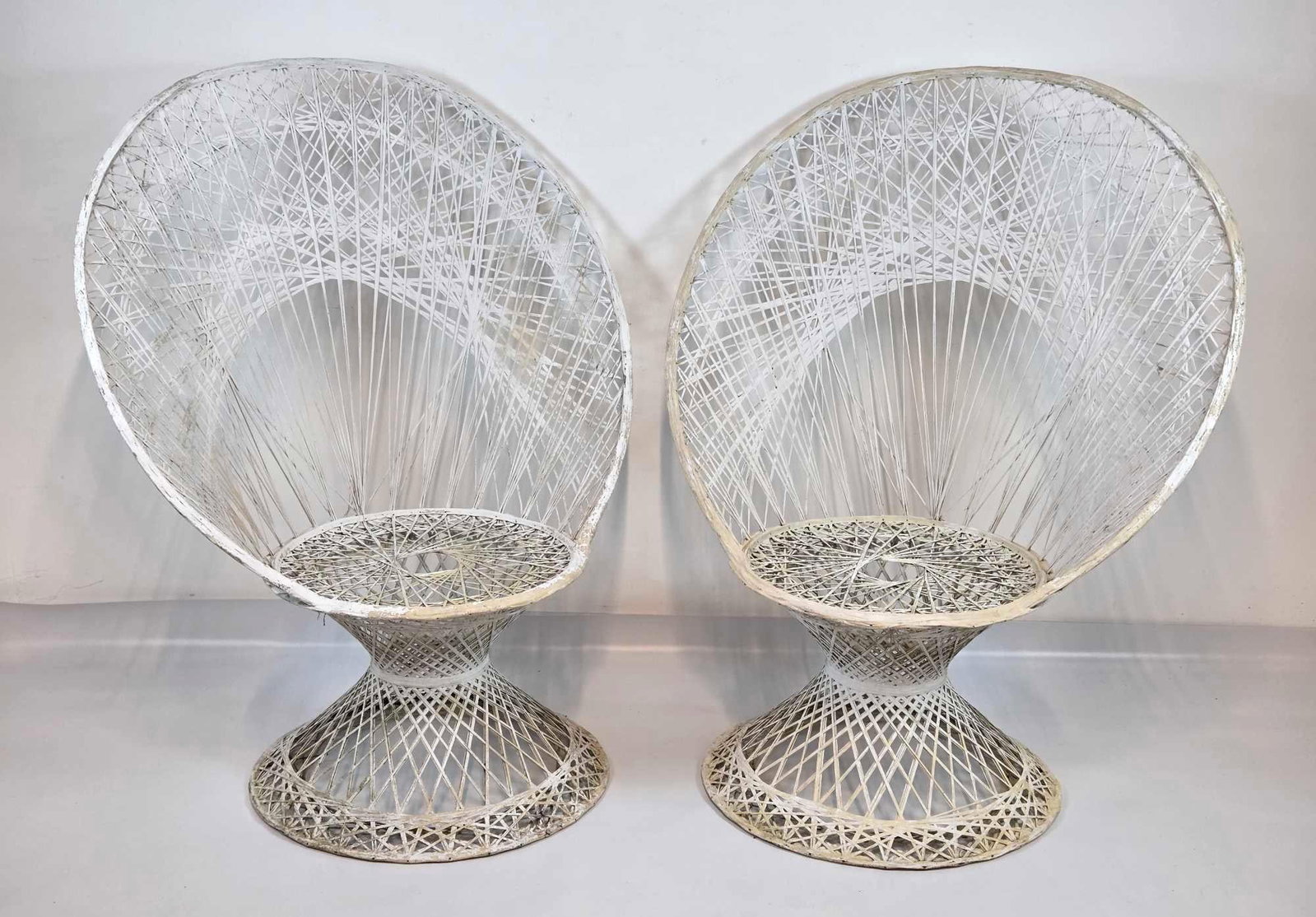 VINTAGE WOODARD SPUN FIBERGLASS PEACOCK CHAIRS, PAIR: Pair of mid-century modern white openwork spun fiberglass lounge chairs designed with dramatic oversized fan backs on hour-glass shaped pedestal bases Approximate Dimensions: 48" H X 39.75" W 