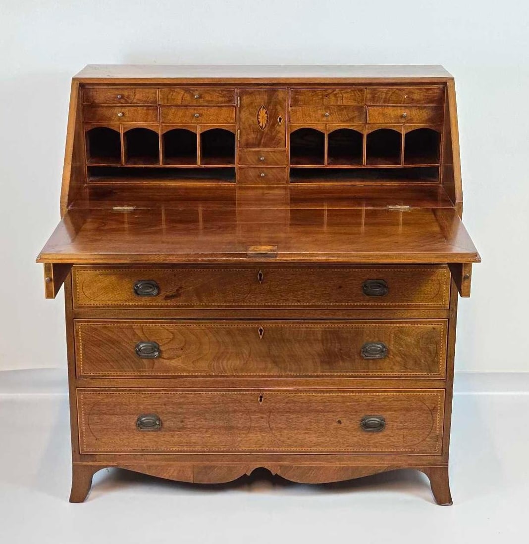 ANTIQUE INLAID MAHOGANY SLANT FRONT DESK: A fine mahogany slant-front writing bureau with a dropdown loper-supported lid opening to a fully fitted interior gallery above three long drawers with oval brass hardware and a shaped bracket base. A