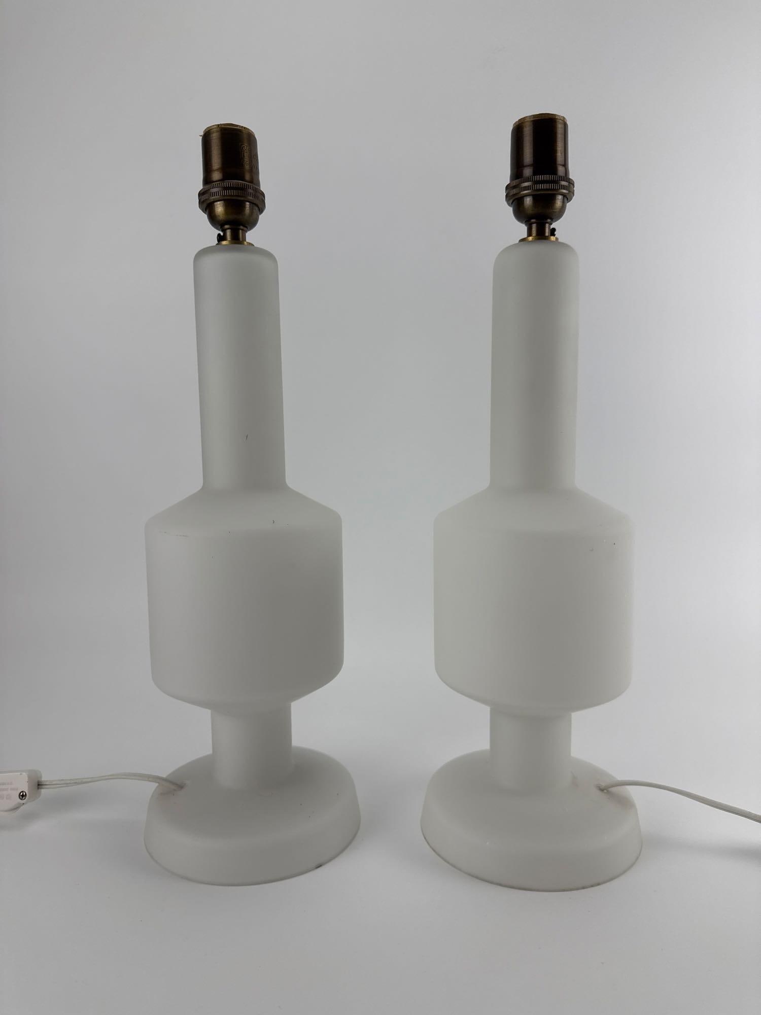PAIR OF VINTAGE SWEDISH FROSTED GLASS TABLE LAMPS: Pair of mid-century modern white satin-finished frosted glass table lamps with a geometric stepped silhouette on circular bases. Approximate Dimensions: 16.5” T x 5” dia Artist or Maker: U
