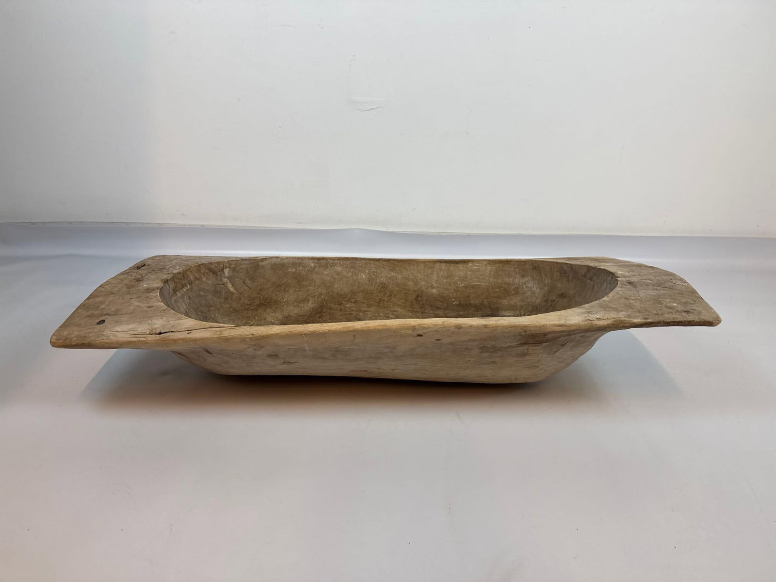 ANTIQUE HAND-CARVED WOODEN DOUGH BOWL, PRIMITIVE TRENCHER: Large hand-hewn oblong dough bowl with integral end handles Approximate Dimensions: 8"H x 36"L x 16"W Condition: Age cracks and checking to wood, surface wear and drying splits consistent 