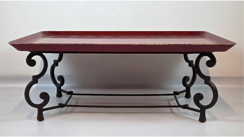 RED AND GILT PAINT DECORATED LARGE WOOD TRAY TOP COFFEE TABLE WITH SCROLLED IRON BASE: Large 20th-century low cocktail table with a removable hand-decorated red and gold leaf border wooden tray resting on a heavy scrolling wrought iron base Approximate Dimensions: 17.5" H X 45" 
