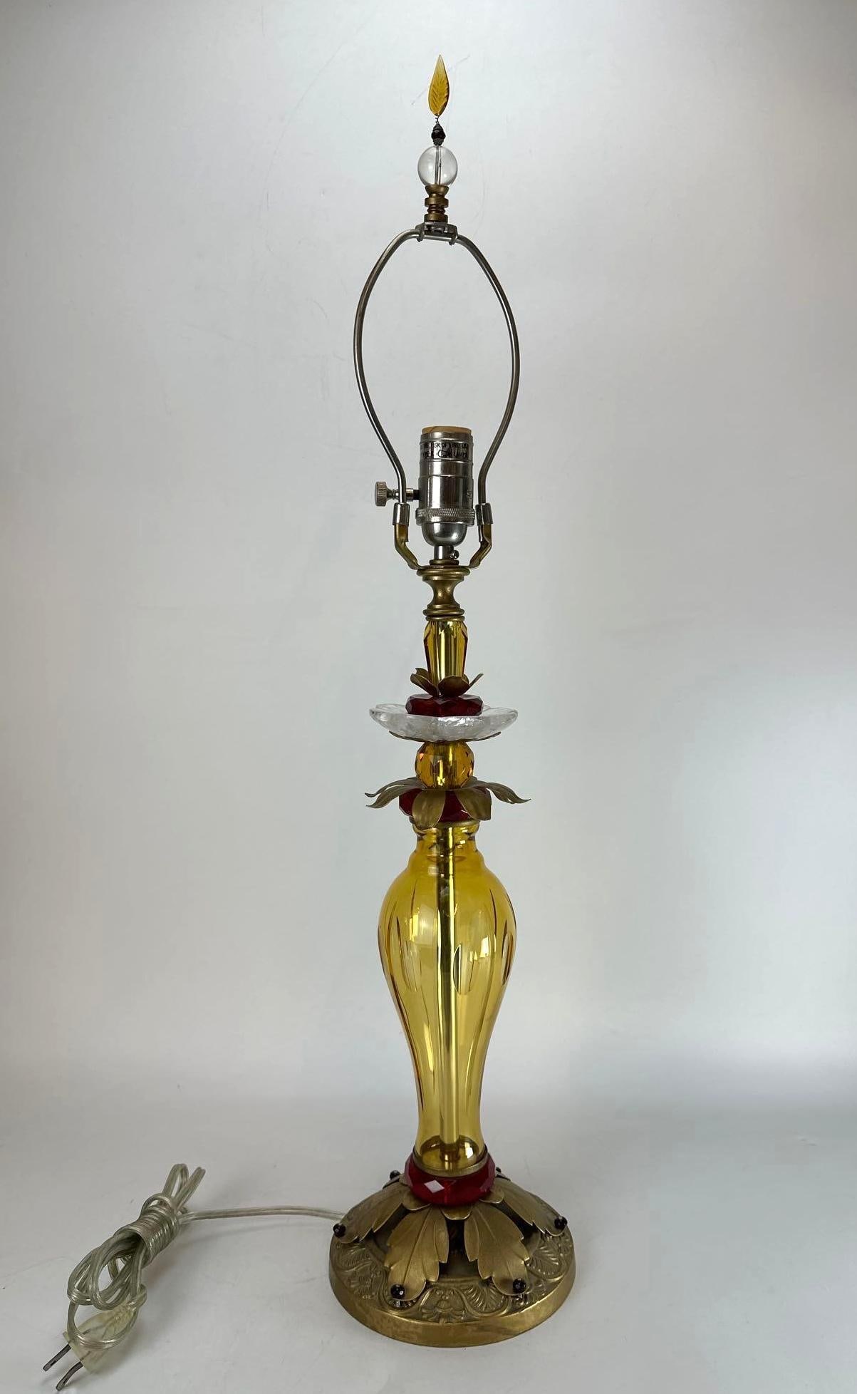 VINTAGE HOLLYWOOD REGENCY AMBER GLASS AND BRASS TABLE LAMP: *Vintage mid-century Hollywood Regency table lamp crafted by Stiffel featuring a ribbed amber glass urn body accented with ruby red cut-glass spacers, an ornate foliate brass-plated base, matching flo