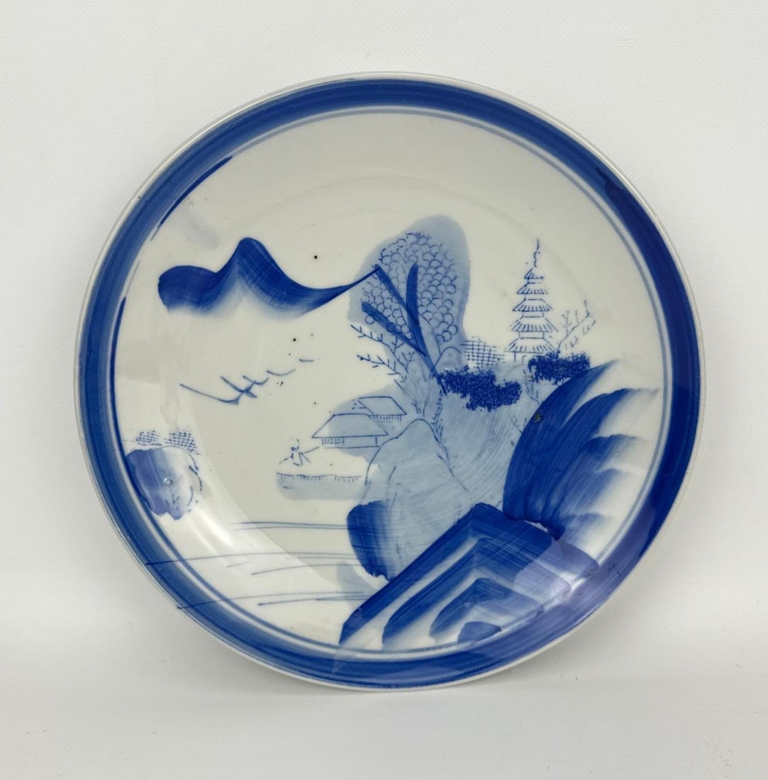 JAPANESE ARITA PORCELAIN BLUE AND WHITE SOMETSUKE LANDSCAPE DISH: *Underglaze blue hand-painted porcelain plate depicting a traditional mountain, river, and pagoda sansui landscape scene. Approximate Dimensions: 1.5” H X 9.5” Dia. Artist or Maker: Unkno