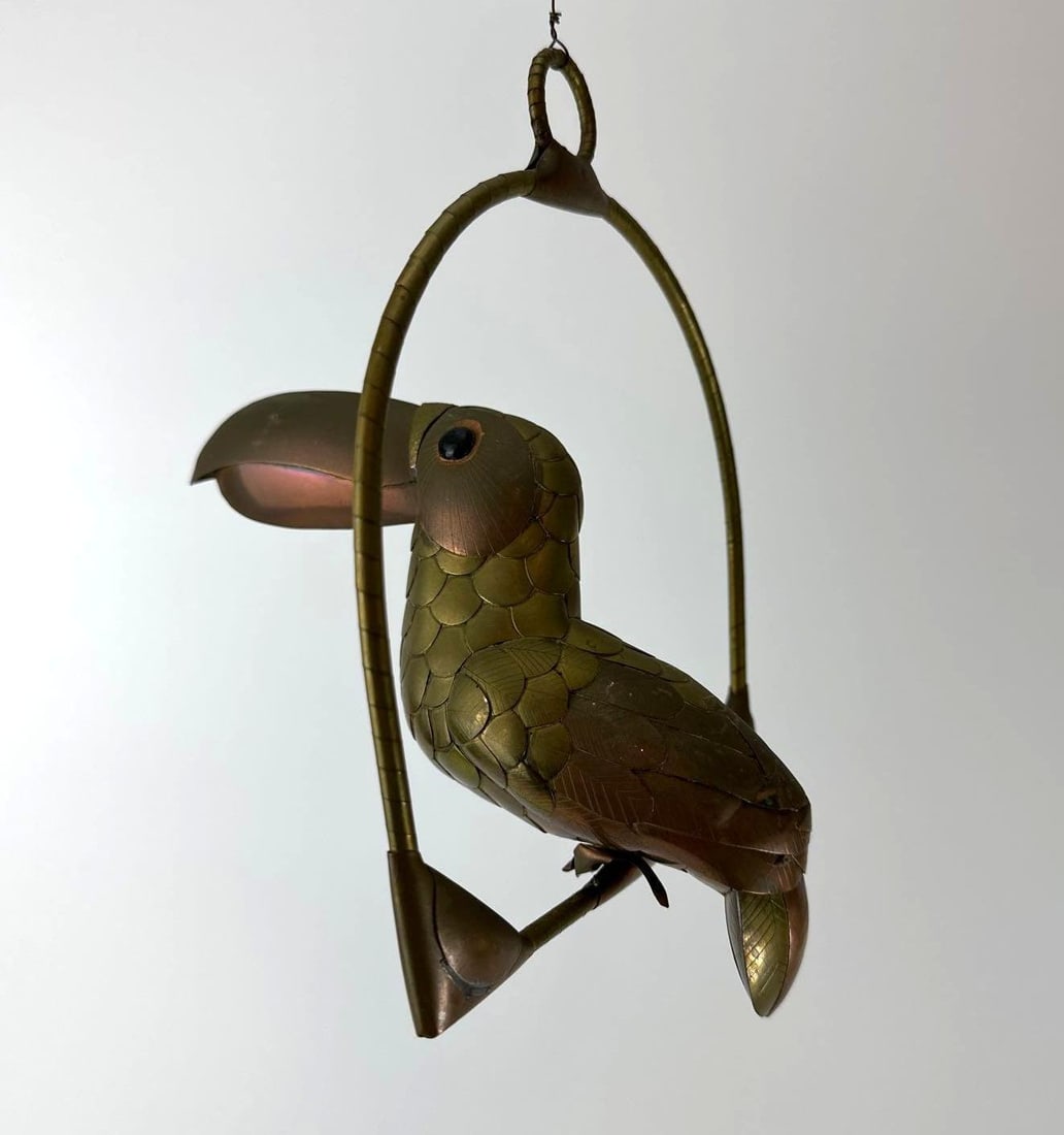 SERGIO BUSTAMANTE STYLE BRASS AND COPPER TOUCAN ON HANGING PERCH SCULPTURE 8": Mid-century Mexican modern 8-inch articulated brass and copper toucan bird suspended from a circular hoop perch Approximate Dimensions: 8”x8” Artist or Maker: Unknown Prov
