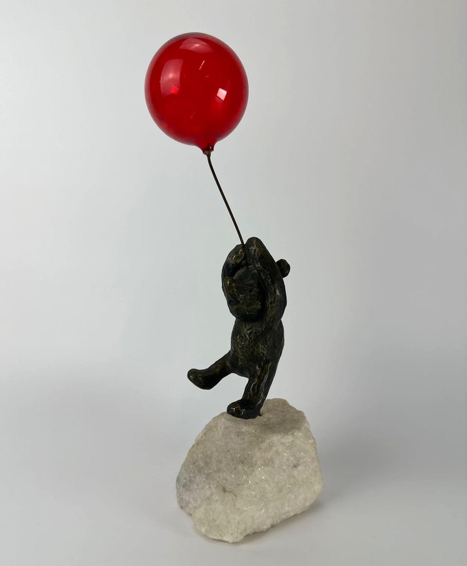 CONTEMPORARY BRONZE BEAR WITH RED GLASS BALLOON ON QUARTZ BASE: Whimsical 12-inch patinated bronze bear floating with a vibrant red glass balloon mounted on a natural white quartz stone base Approximate Dimensions: 4”x4”x12” Artist or Maker: Unkn