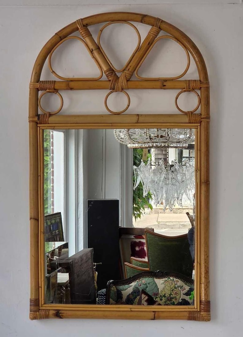 VINTAGE ARCHED BAMBOO AND RATTAN BENTWOOD WALL MIRROR: Vintage coastal modern wall mirror with a rectangular glass pane beneath an arched openwork bentwood rattan pediment featuring loop and ring motifs. Approximate Dimensions: 36" H X 21.5" W Art