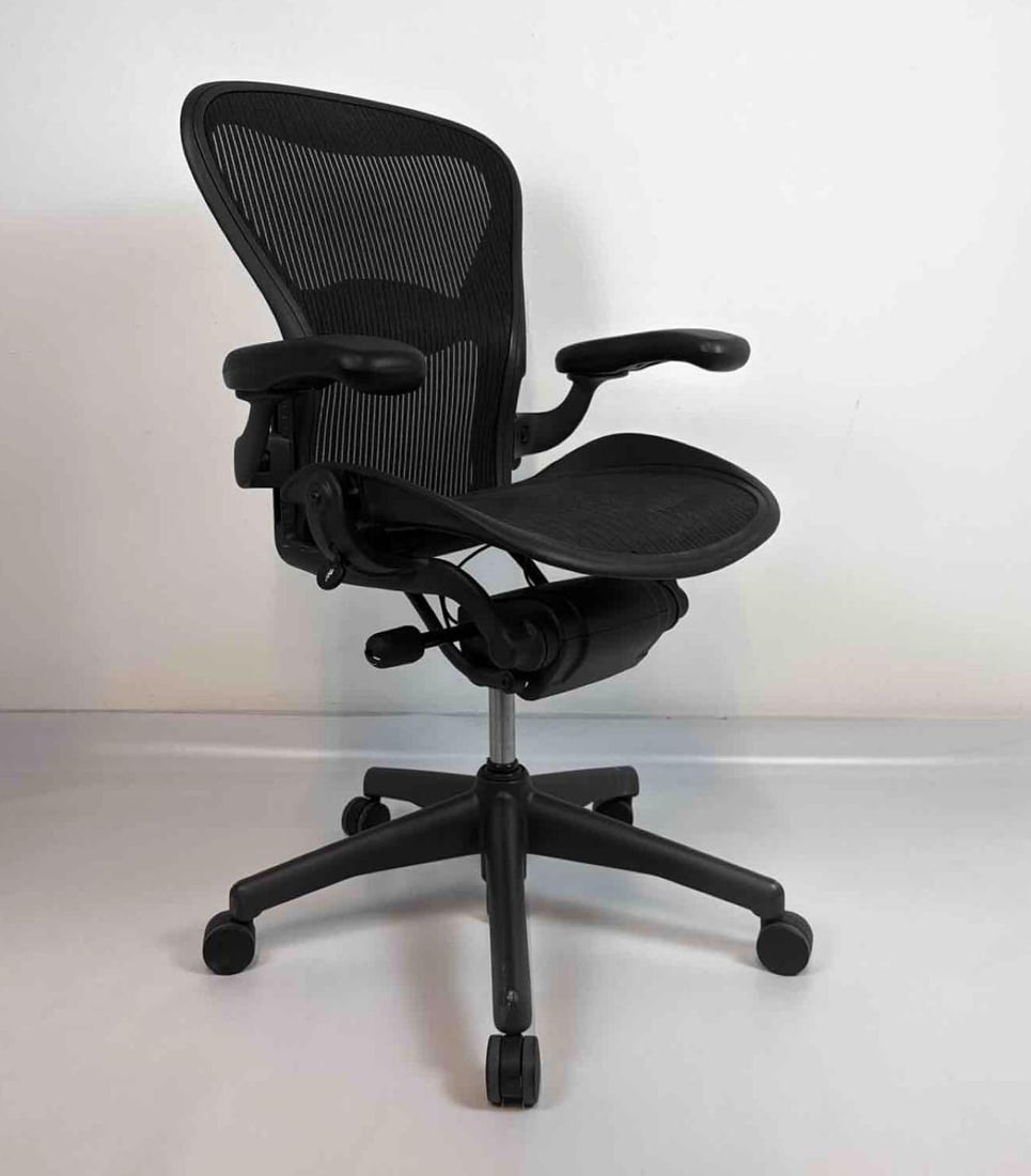 HERMAN MILLER AERON ERGONOMIC BLACK MESH OFFICE DESK CHAIR: Black Pellicle mesh ergonomic swivel desk chair with adjustable arms, posturefit back support, and caster base Approximate Dimensions: 42” H X 26” W X 30” D Artist or Maker: Herman M