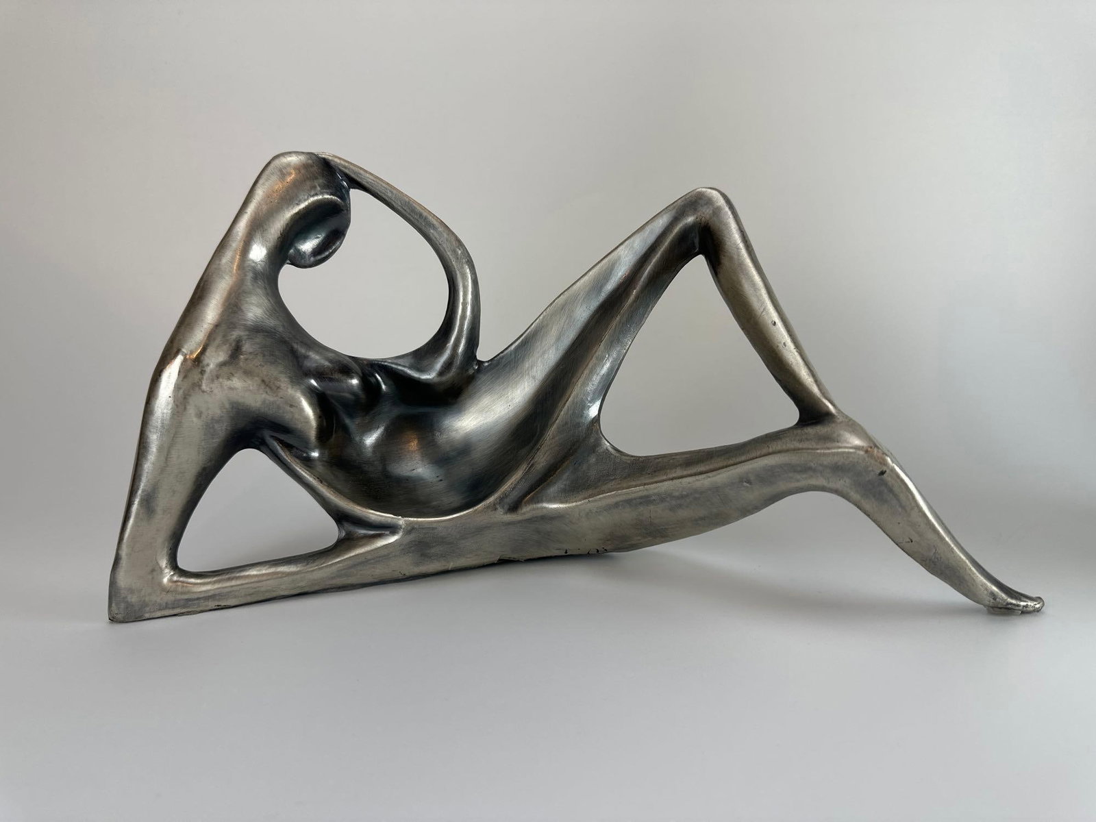 DEL CORSO CAST ALUMINUM RECLINING FIGURE SCULPTURE: Modernist cast aluminum sculpture of a stylized reclining figure Approximate Dimensions: 7" H x 13" W x 5" D Artist or Maker: Del Corso Provenance: From a New York Collector Notes: Althoug