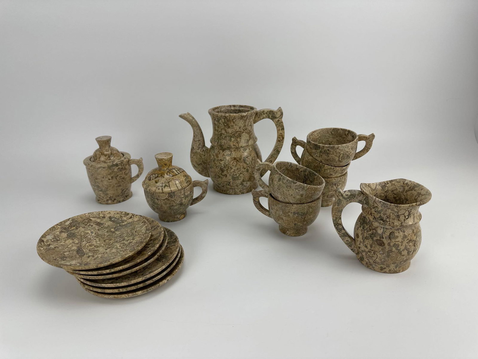 CARVED FOSSIL MARBLE MINIATURE TEA SET: Miniature tea service carved from mottled fossil marble, including teapot, creamer, sugar, cups and saucers Approximate Dimensions Largest Item: 7" H x 4" W x 4" D (teapot) Artist or Maker