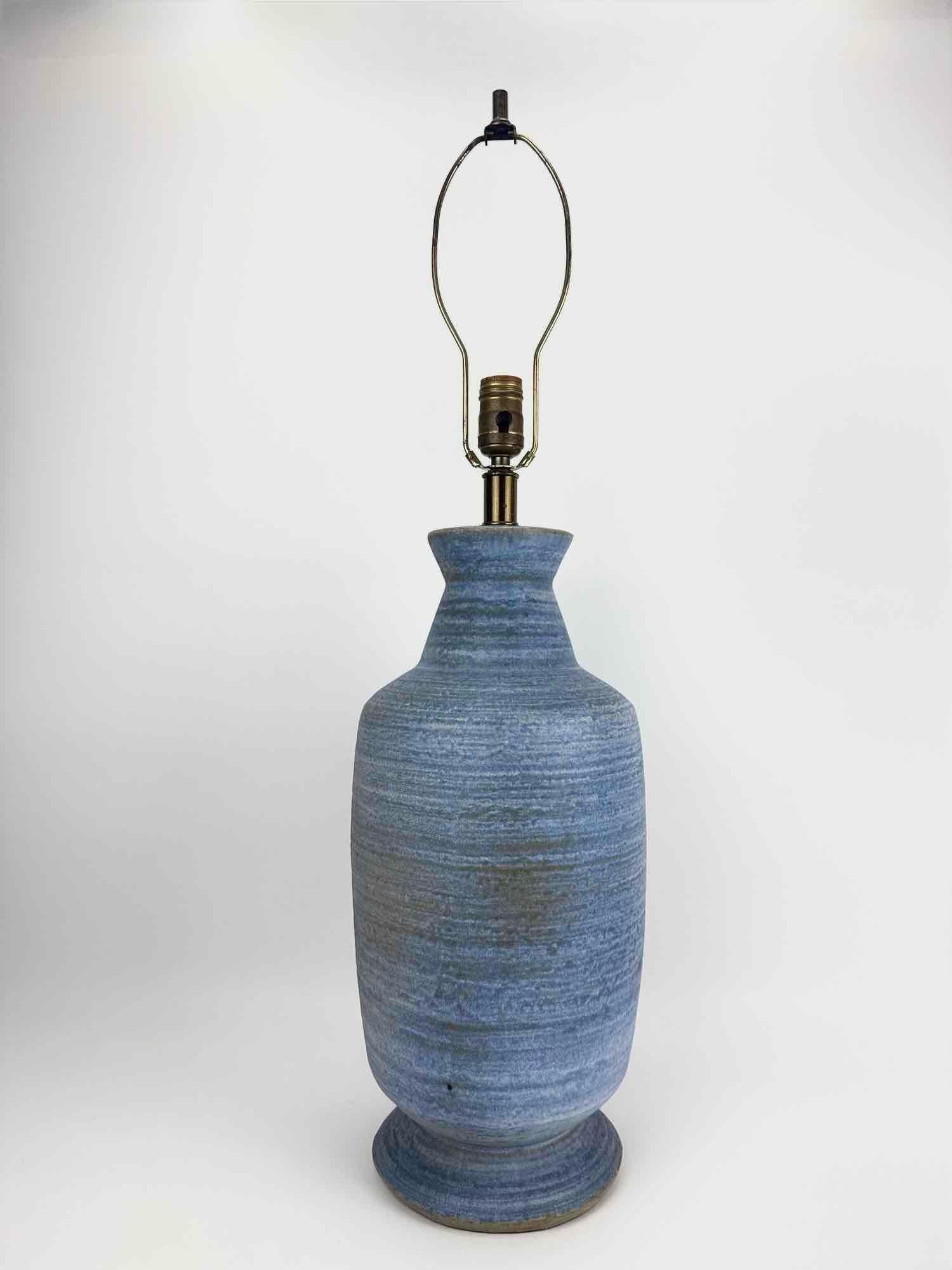 BLUE CERAMIC UNGLAZED TABLE LAMP: Mid century studio ceramic table lamp of baluster form in a matte striated blue glaze with brass fittings Approximate Dimensions: 23.5" H (32" H to top of harp) x 8.5" Dia. Artist or Maker