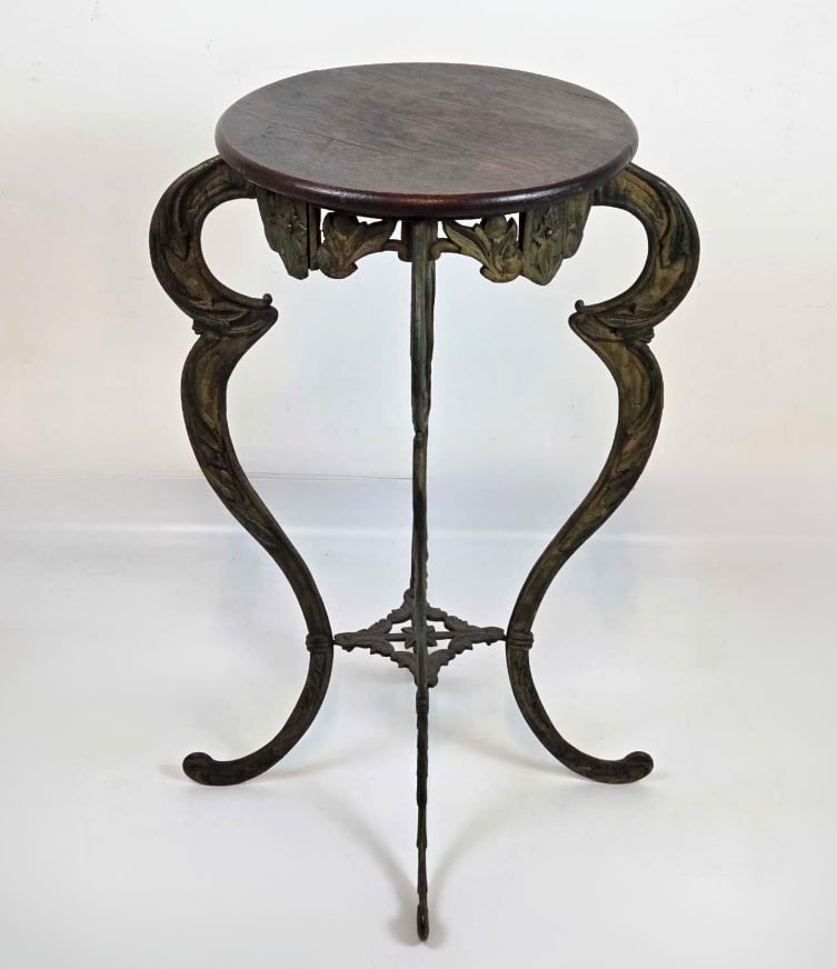 ART NOUVEAU-STYLE IRON PEDESTAL PLANT STAND WITH WOOD TOP: Iron pedestal stand with circular wood top and whiplash cabriole legs,. Approximate Dimensions: 28.25" H X 19" Dia. Artist or Maker: Unknown Provenance: From the estate of a prominent New York
