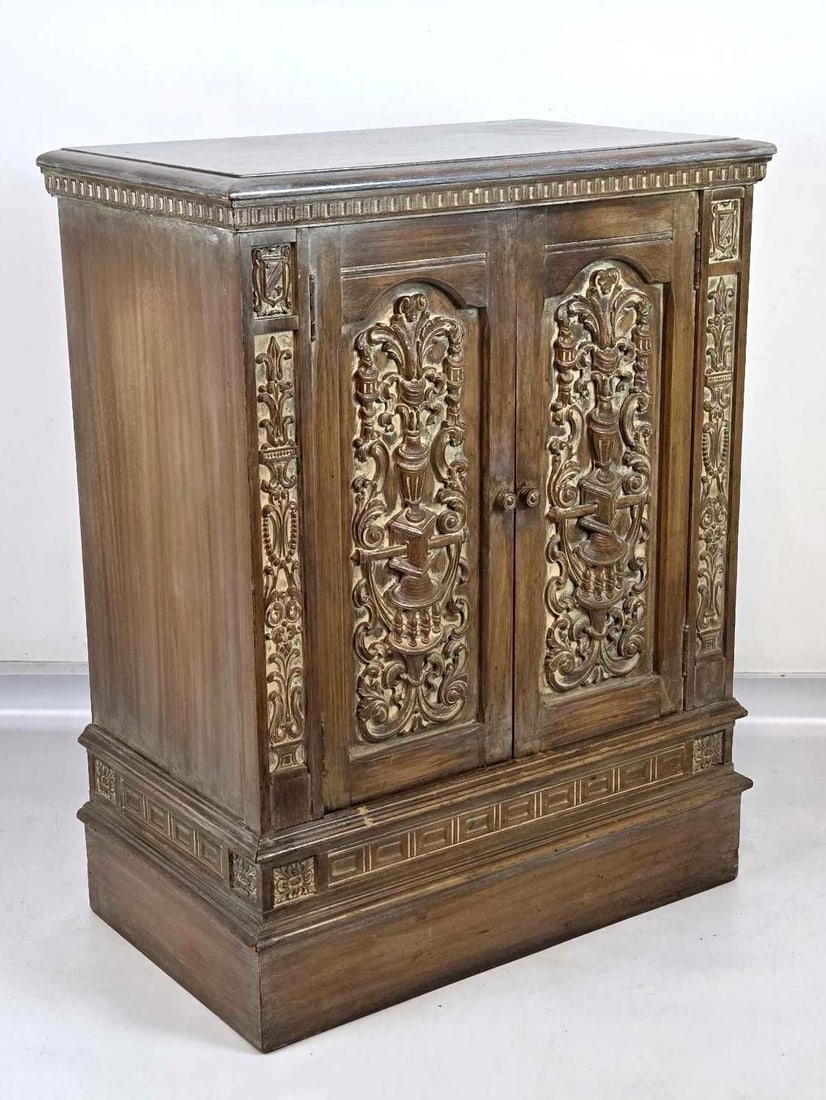 SPANISH RENAISSANCE-STYLE CARVED WOOD BAR CABINET: Spanish Renaissance-style carved wood two-door bar cabinet with foliate panels and spiral columns over a shelved interior. Approximate Dimensions: 35.5" H X 27.75" W X 16.25" D Artist or M