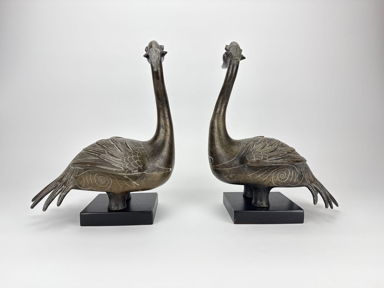 PAIR OF ANTIQUE CHINESE ARCHAISTIC BRONZE BIRD FIGURES: *Pair of vintage Chinese archaistic style cast bronze waterbird or crane sculptures finished with incised geometric cloud and feather details, mounted on square black wooden plinth bases, with conditi