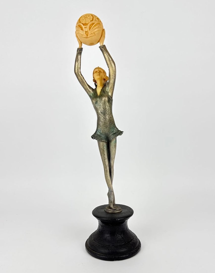 ART DECO STYLE CHRYSELEPHANTINE BRONZE DANCER SCULPTURE: *Art Deco style chryselephantine sculpture depicting an acrobatic female dancer in mid-pose, holding a carved geometric ball aloft. Approximate Dimensions: 17.5” H X 5” W X 5.75” D A