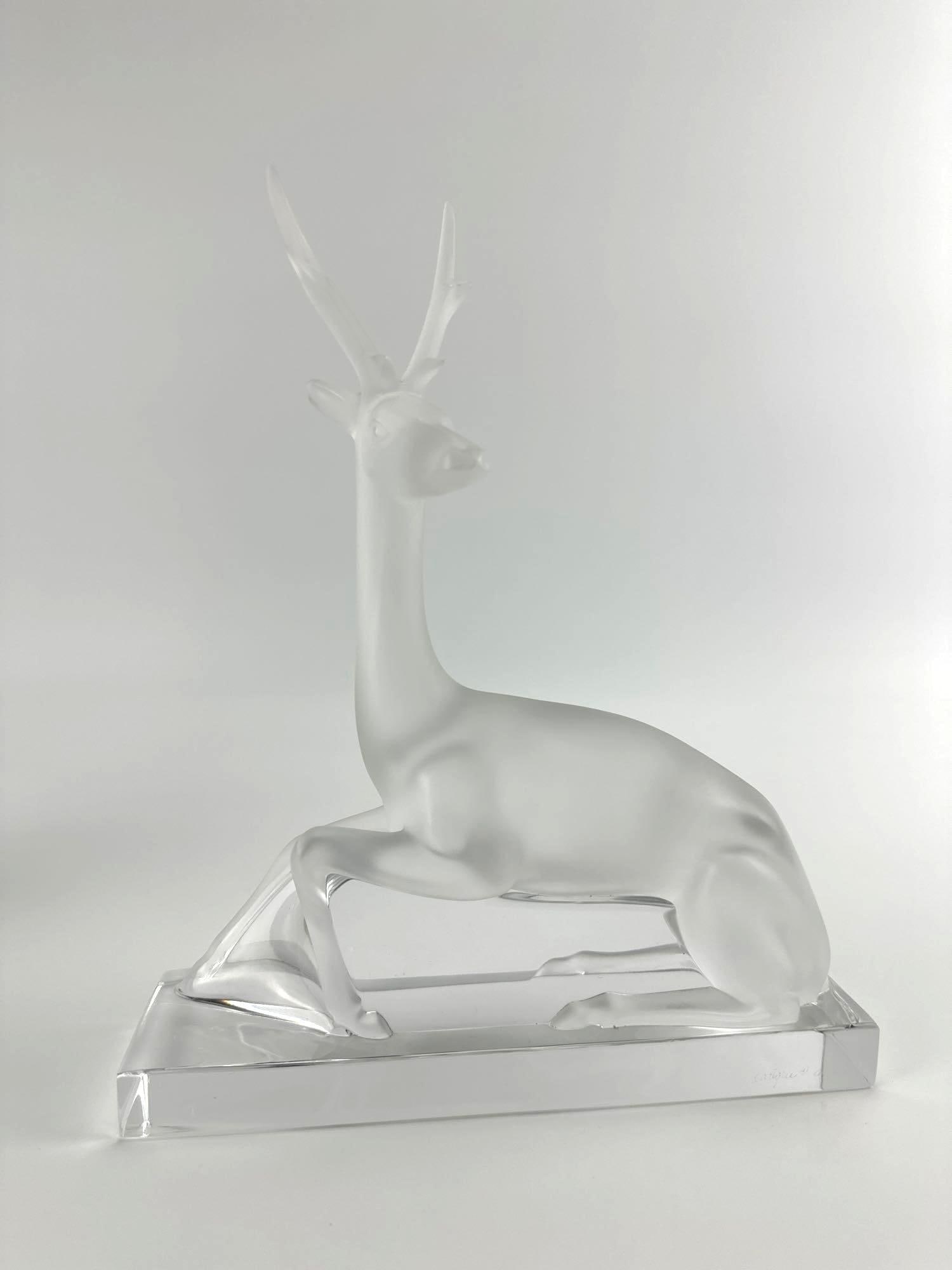 LALIQUE FRANCE FROSTED CRYSTAL CERF STAG FIGURE SCULPTURE: *French frosted and polished clear crystal recumbent stag figurine raised on a rectangular base, etched signature to the side Approximate Dimensions: 8.5”x2.5”x10.5” Artist or Maker: