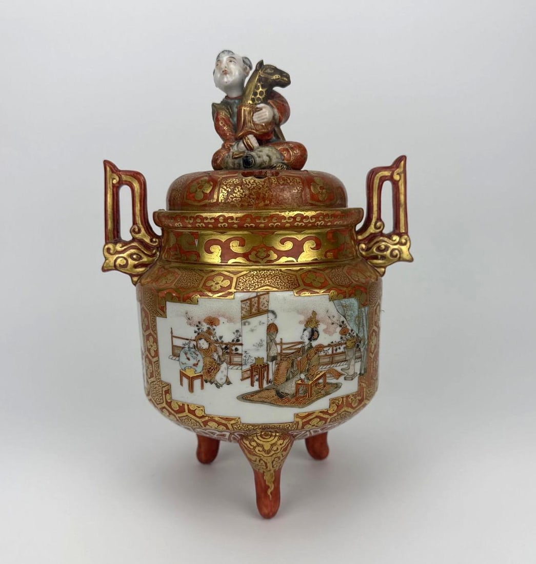 ANTIQUE JAPANESE KUTANI PORCELAIN KORO INCENSE BURNER WITH REPAIR: *Meiji period hand-painted iron-red and gilt-ground tripod ceramic censer with figural boy finial, loop handles, and narrative painted panels depicting interior courtyard figures Note: previous repair