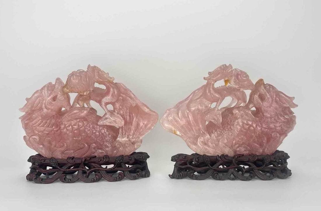PAIR OF CARVED ROSE QUARTZ FIGURES ON WOOD STANDS: Pair of carved rose quartz figural carvings on fitted wood stands Approximate Dimensions: 8.25" H x 10" W x 2.5" D Artist or Maker: Unknown Provenance: From the estate of a prominent New Y