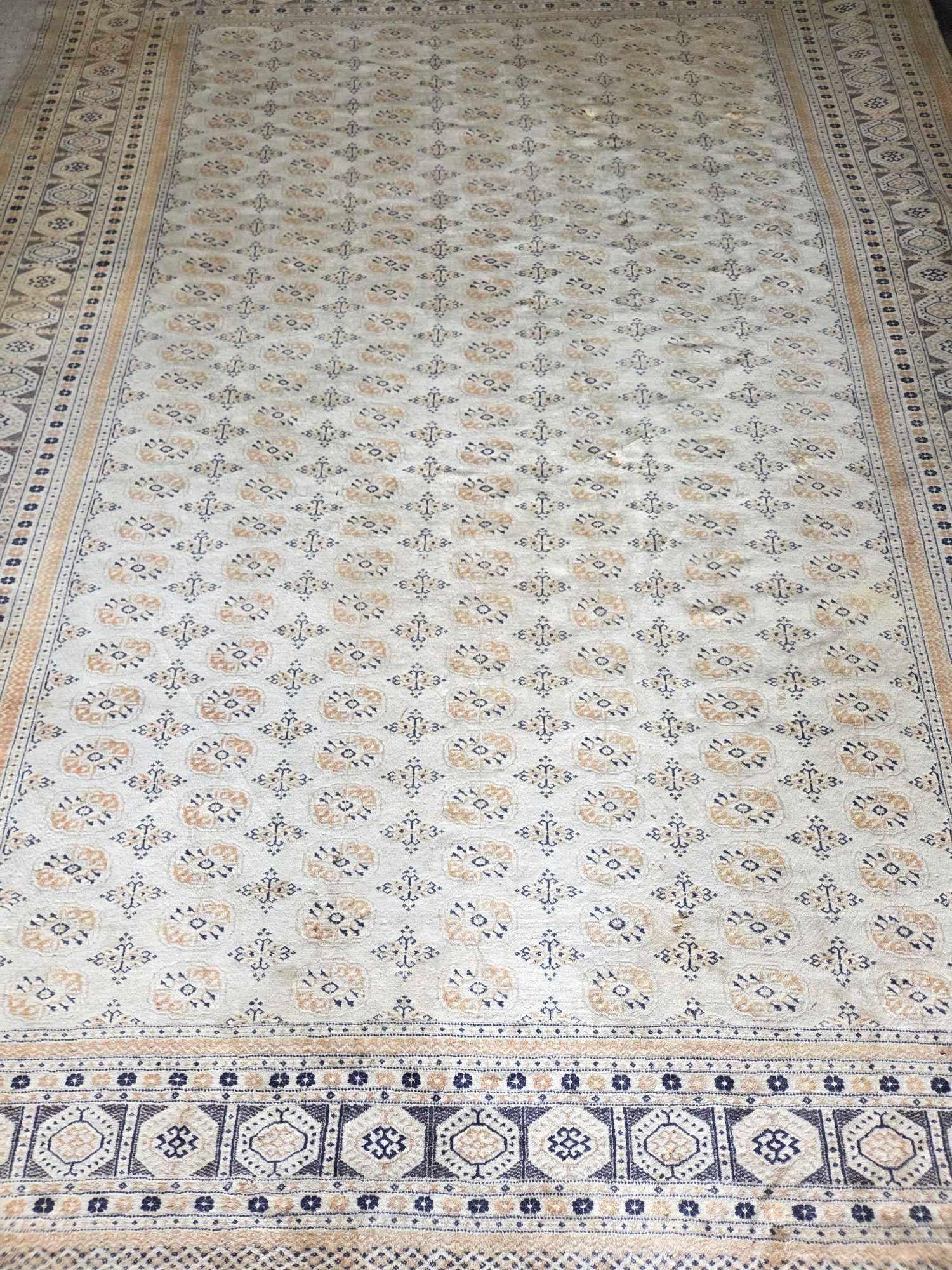 VINTAGE BEIGE GROUND BOKHARA ROOM SIZE WOOL RUG: Vintage Bokhara room-size hand-knotted wool rug with rows of octagonal guls in tan and navy on a soft beige ground, framed by multiple geometric guard borders Approximate Dimensions: 9' x 12' 