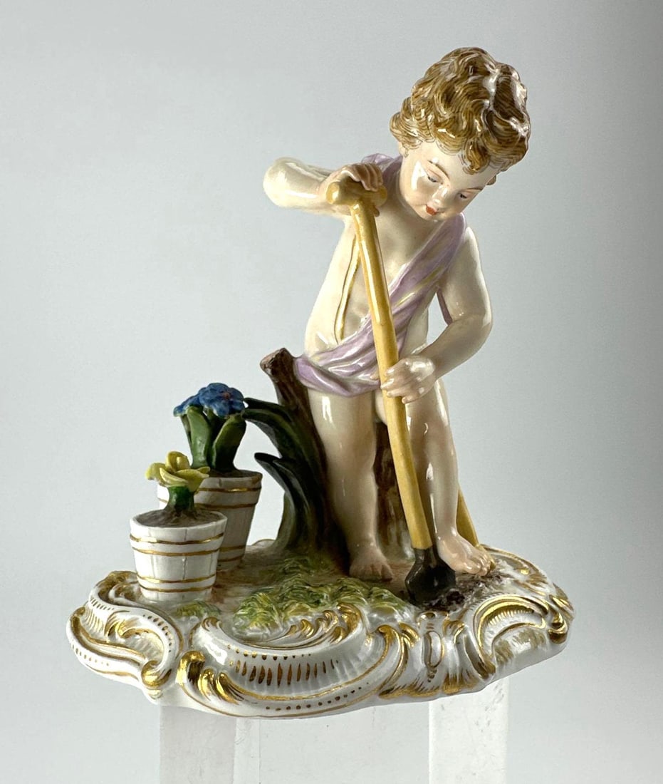 MEISSEN GARDENER CHILD PORCELAIN FIGURINE, CROSSED SWORDS MARK: Polychrome and gilt porcelain figure of a gardener child leaning on a spade beside two flower tubs, on a pierced rococo scroll base from the Meissen gardener children (Gaertnerkinder) series, Approxim