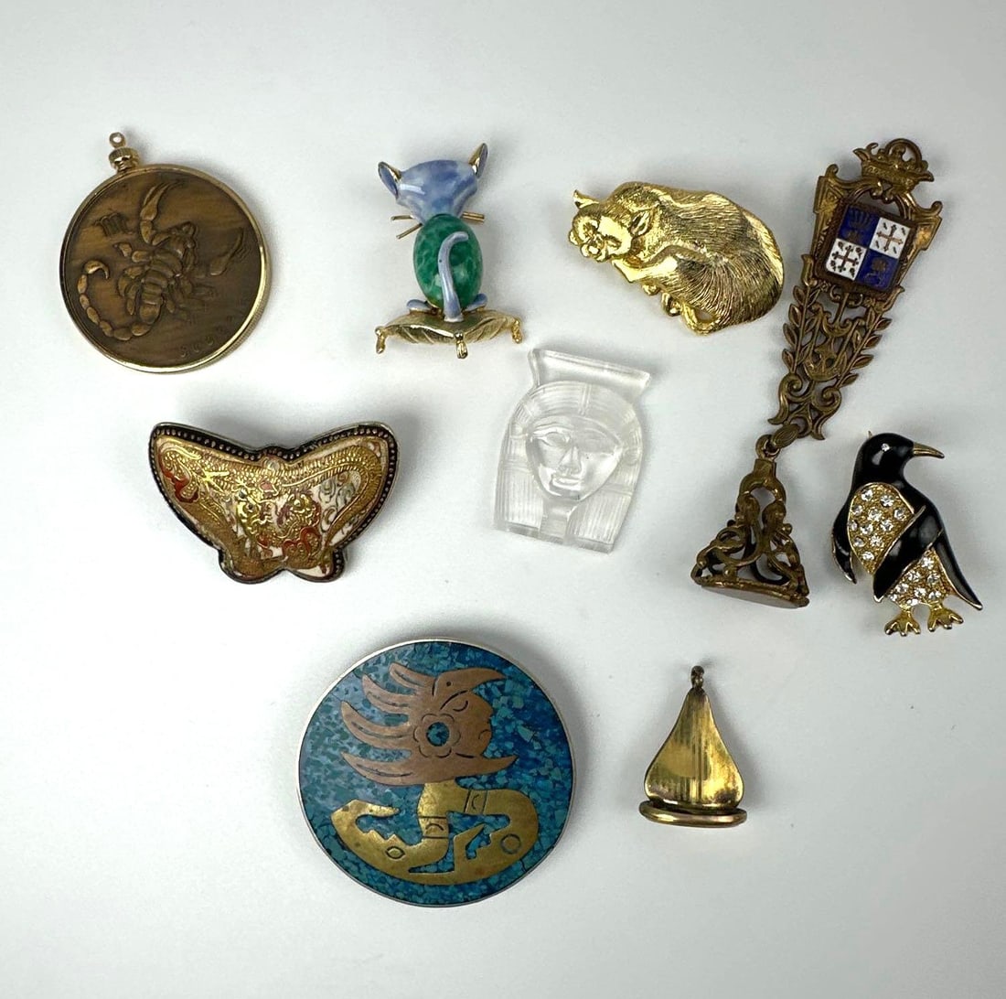 GROUP OF NINE VINTAGE BROOCHES AND PINS, STERLING, ENAMEL, GLASS: Group of nine vintage brooches, pins and pendants, including a bronze Scorpio zodiac pendant, a turquoise enamel disc brooch marked sterling, enamelled penguin and cat figurals, a frosted glass pharao