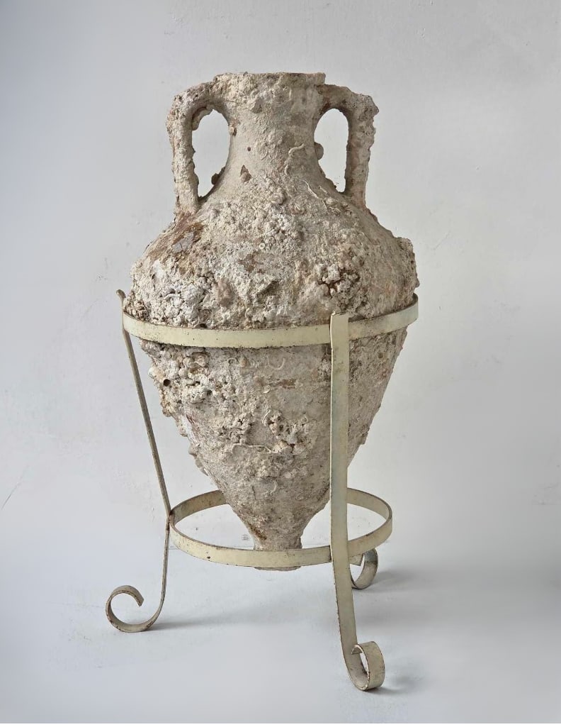 MARINE ENCRUSTED POTTERY TRANSPORT AMPHORA ON WROUGHT IRON STAND, ROMAN STYLE: Pottery transport amphora of classical form, covered in heavy calcareous marine encrustation of shell and coral growth. Approximate Dimensions: amphora 22" H x 12" Dia.; overall on stand 25