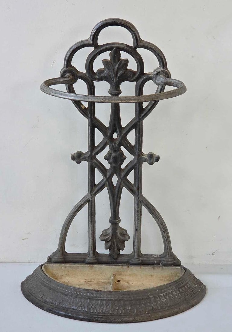 ANTIQUE CAST IRON UMBRELLA AND CANE STAND, FRANCE: Cast iron umbrella and cane stand of demilune form, pierced back panel of interlaced Gothic tracery. Approximate Dimensions: 25 1/2" H x 18" W x 10 1/4" D Artist or Maker: Unknown foundry.