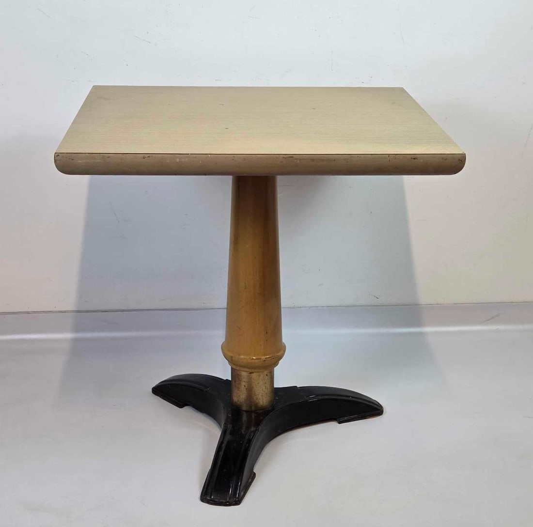 VINTAGE PEDESTAL CAFE TABLE, BLOND LAMINATE TOP ON TURNED COLUMN AND CAST IRON TRIPOD BASE (1 of 2): a vintage pedestal cafe or bistro table. Approximate Dimensions: 29.5” H x 29.75” W x 25.75” D Artist or Maker: Unsigned Provenance: From a New York Collector Notes: Although care is