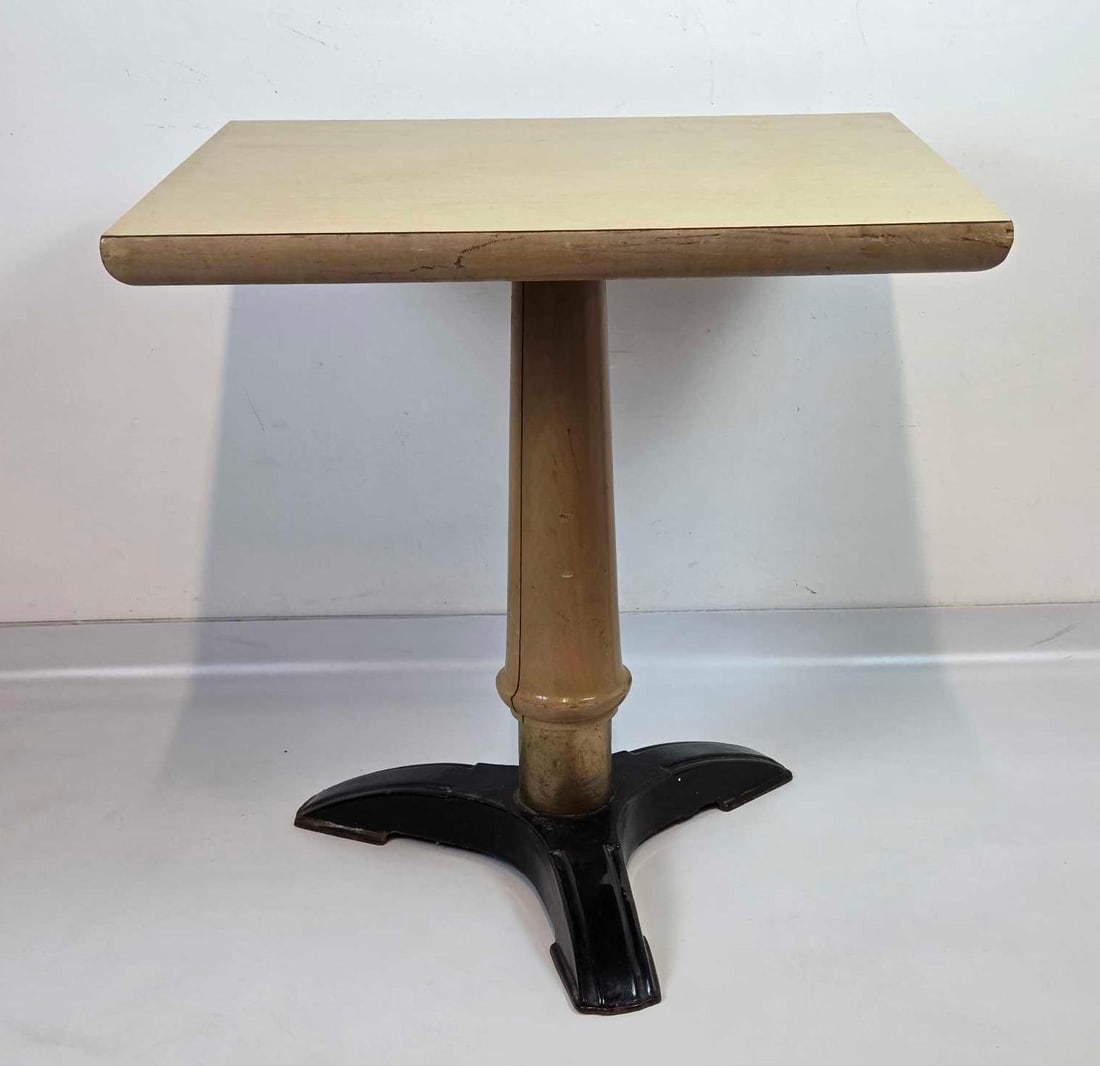 VINTAGE PEDESTAL CAFE TABLE, BLOND LAMINATE TOP ON TURNED COLUMN AND CAST IRON TRIPOD BASE(2 of 2): a vintage pedestal cafe or bistro table. Approximate Dimensions: 29.5” H x 29.75” W x 25.75” D Artist or Maker: Unsigned Provenance: From a New York Collector Notes: Although care is