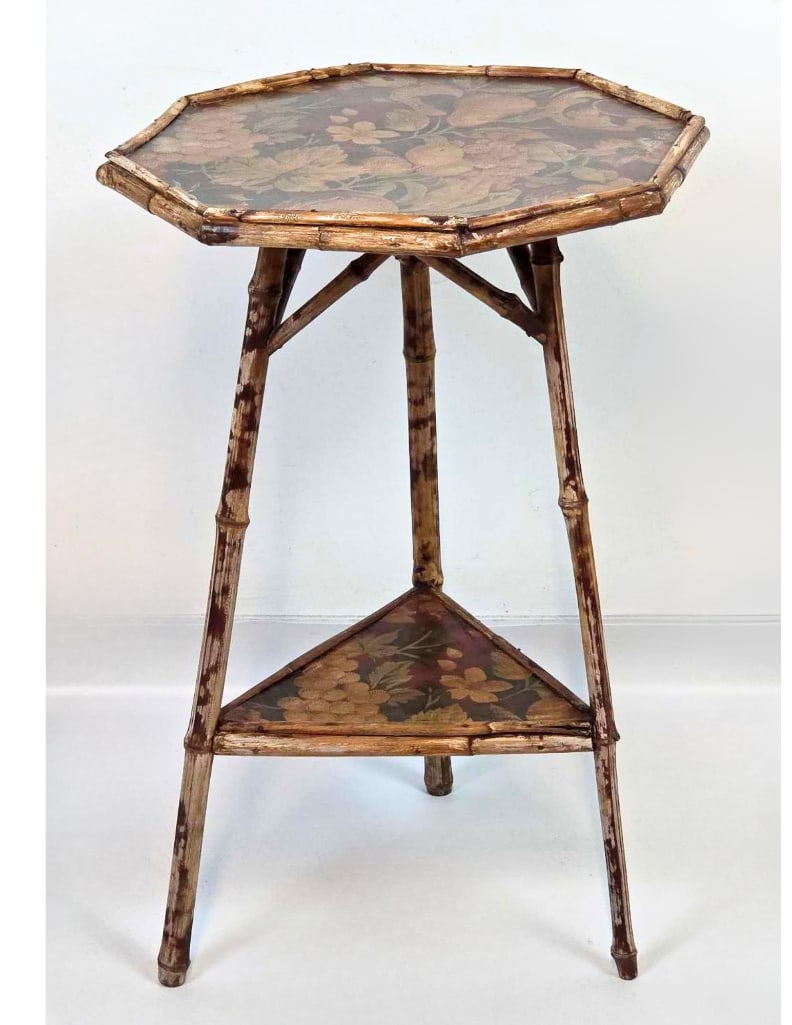VICTORIAN SCORCHED BAMBOO TWO-TIER OCCASIONAL TABLE, OCTAGONAL PAPERED TOP: a Victorian scorched bamboo occasional table, the octagonal top and triangular lower tier faced with a decorative paper. Approximate Dimensions: 26.5” H x 17” W x 17” D Artist or Mak