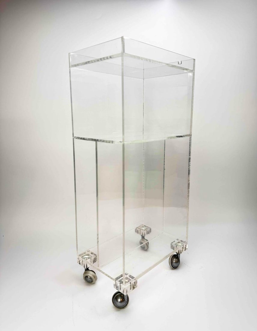 CHARLES HOLLIS JONES STYLE PETITE ACRYLIC CART: A clear, minimalist rectangular form cart on wheels. Approximate Dimensions: 23” H x 7” W x 10.5” D Artist or Maker: Unknown Provenance: A New York Collector Notes: Althou