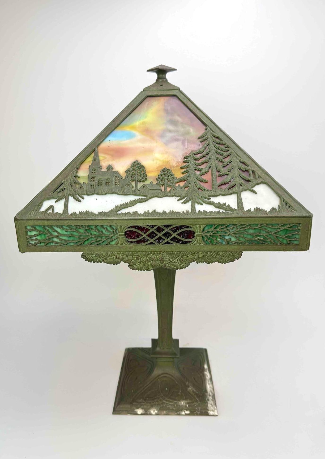 ANTIQUE ARTS AND CRAFTS BRADLEY AND HUBBARD STYLE SLAG GLASS BRONZE TABLE LAMP: clo An antique lamp with a pyramidal, four-sided bronze overlay shade depicting landscape scenes over marbled slag glass panels on a heavy bronze square base. Approximate Dimensions: 23.5” H x 1