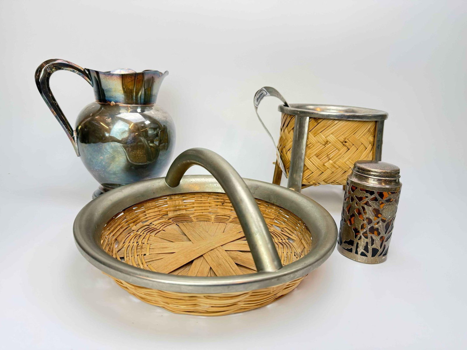 SILVER PLATE SERVING GROUP: 8.75” H X 7.5” W Group of silver plate table and serving pieces including a candelabrum, pitcher, muffineer, silver mounted basket, and wine coaster Artist or Maker: Various, silver plate 