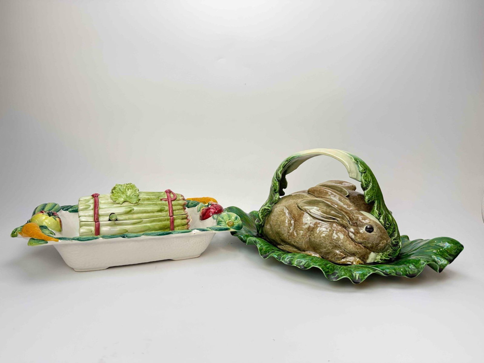 MAJOLICA GROUPING: RABBIT TUREEN, ASPARAGUS DISH & COVERED DISH: Group of three majolica table pieces: a figural covered tureen modeled as a rabbit seated in a cabbage leaf, a trompe loeil asparagus-bundle dish, and a striped lidded serving dish Approx. Dimensions:
