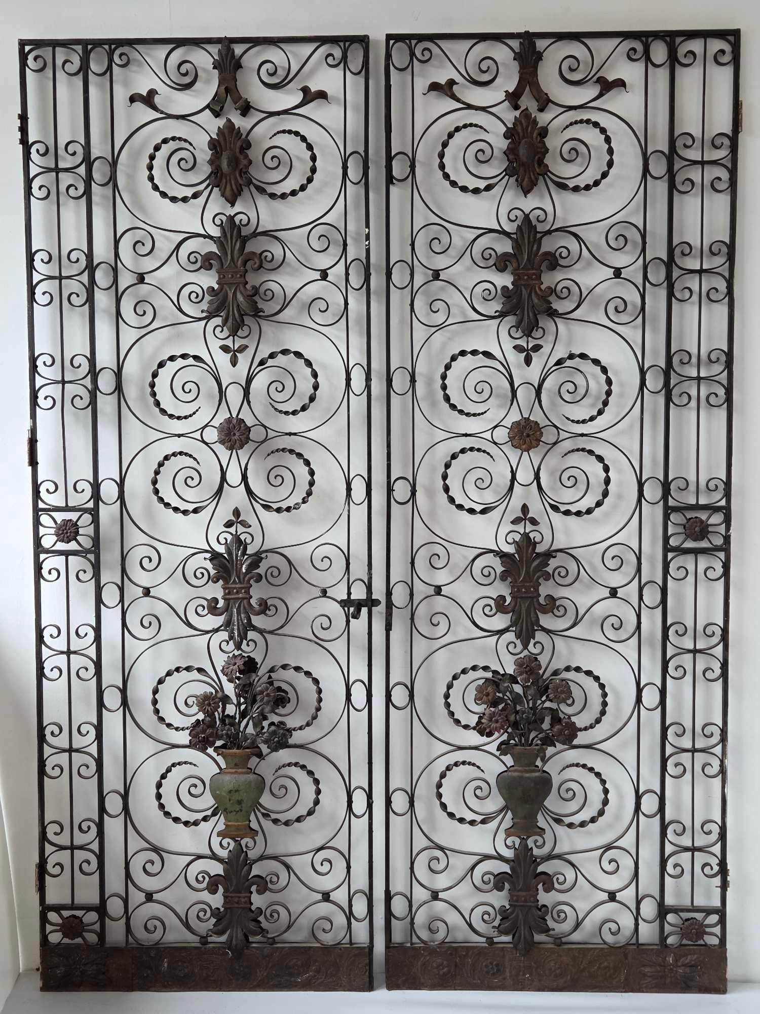 IMPRESSIVE PAIR OF TWO SIDED SCROLL WORK WROUGHT IRON AND TOLE GATES: An impressive pair of tall two sided gate panels in scrolled wrought iron, each centered by applied tole rosettes and foliate mounts within a beaded frame, in an old weathered surface Approximate